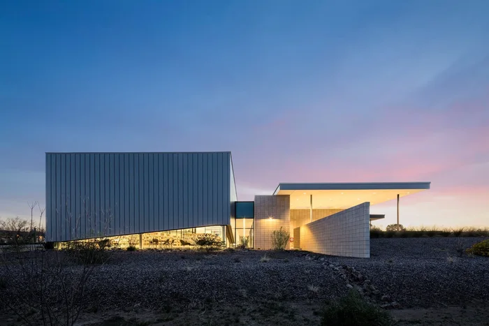 Sahuarita Regional Library at dusk: a metal-clad box beside a low glazed wing, lit from within.